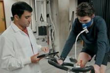 A student conducts physiology research with an athlete using a bicycle