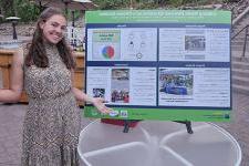 Sidney Barbier st和s next to her poster presentation.