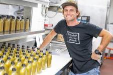 Cole Millington posing next to hot sauce bottles in a commercial kitchen