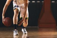 image of a basketball player from the neck down crouched and dribbling.