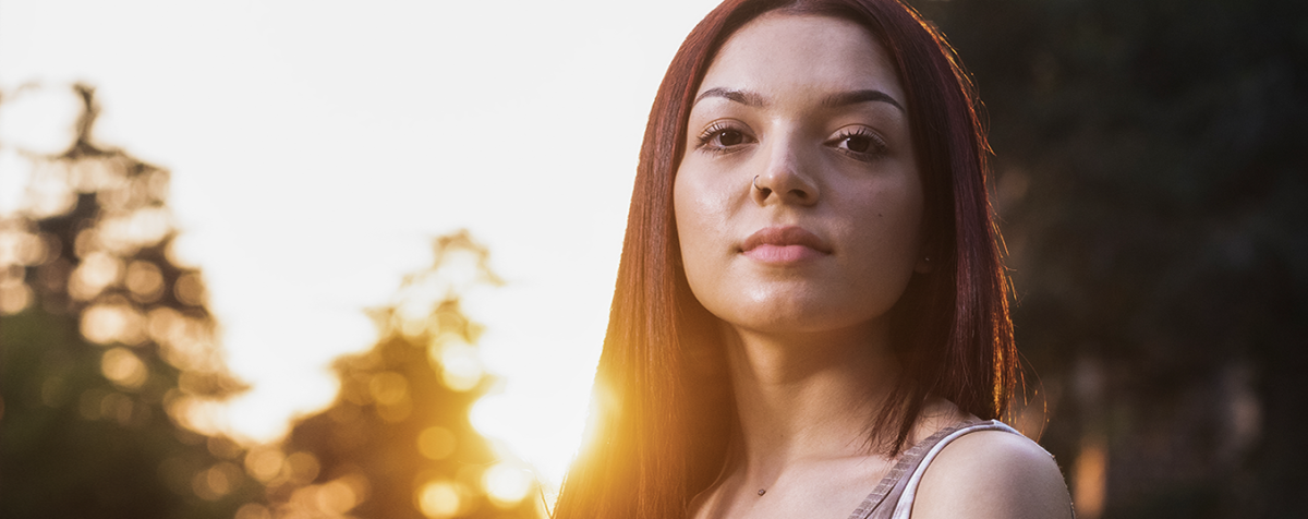 female student with sun setting in background